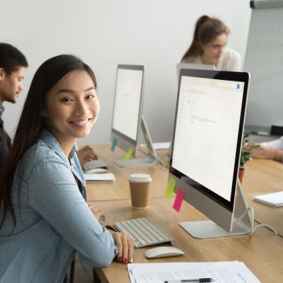 Smiling asian office employee looking at camera working with colleagues