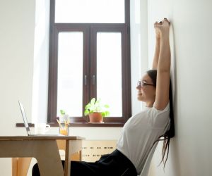 Businesswoman stretching at her desk in a bright, modern office, taking a mindful break to support work-life balance and wellbeing.Businesswoman stretching at her desk in a bright, modern office, taking a mindful break to support work-life balance and wellbeing.