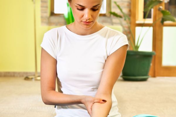 Happy young woman doing  arm self massage at home. Healthy life.