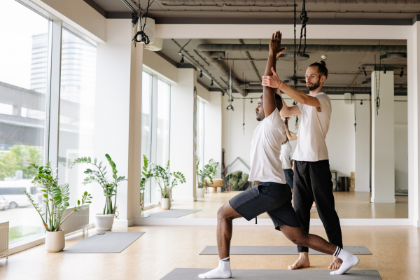 A male yoga instructor teaching a client in an office setting