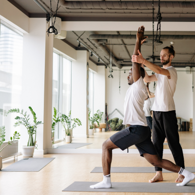 A male yoga instructor teaching a client in an office setting