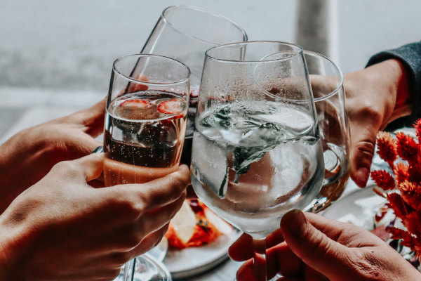 close up of four hands holding glasses showing friends celebrating with alcohol free drinks