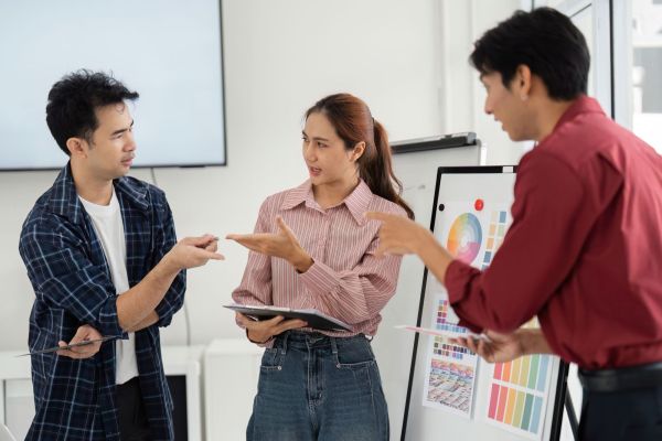 Three people in a workplace setting talking with each other in an engaged manner