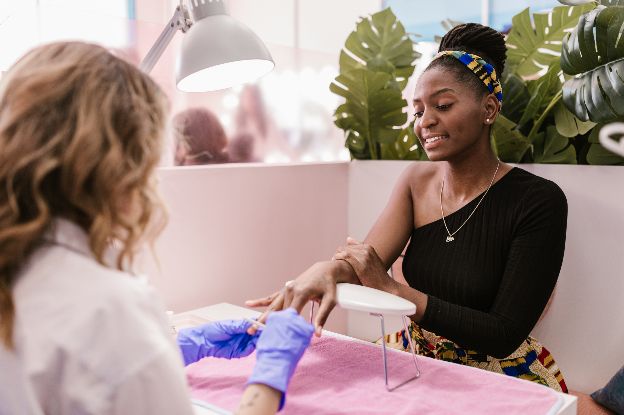 Nail technician providing a workplace manicure to an employee at a desk or table