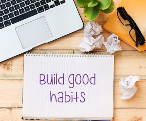 desk with computer eye glasses and note pads with words Build Good Habits written on it