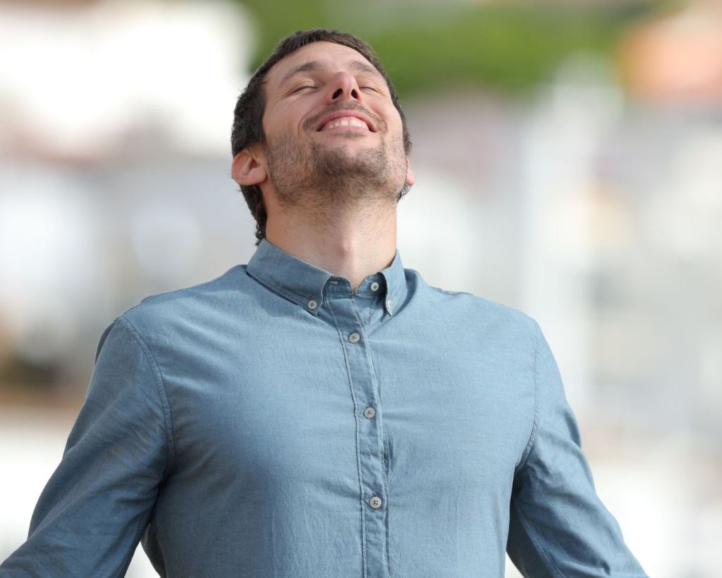 man in blue shirt with eyes closed looking happy and well
