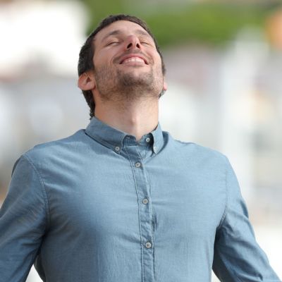 man in blue shirt with eyes closed looking happy and well